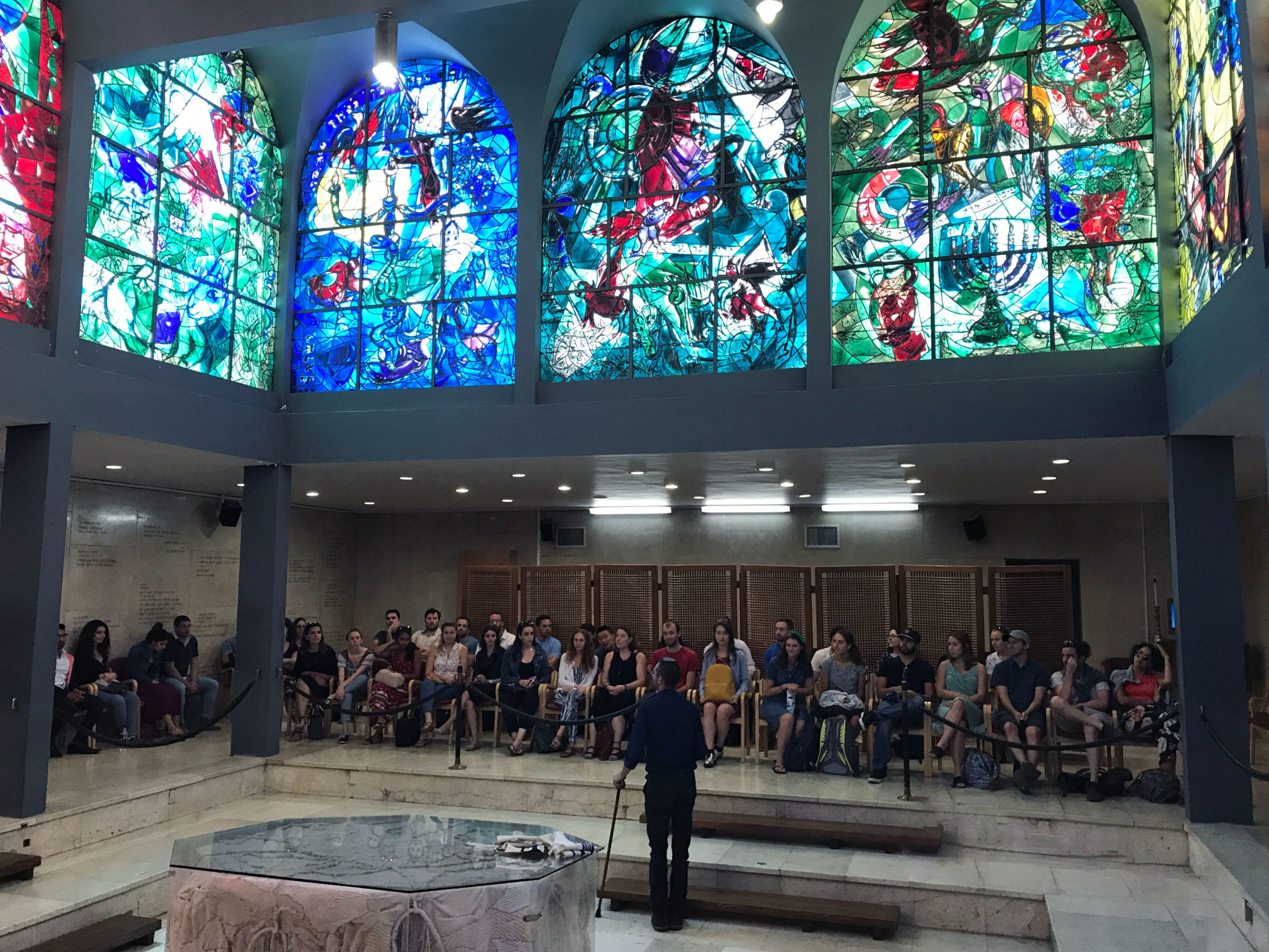 People gathered in room with large stained glass windows
