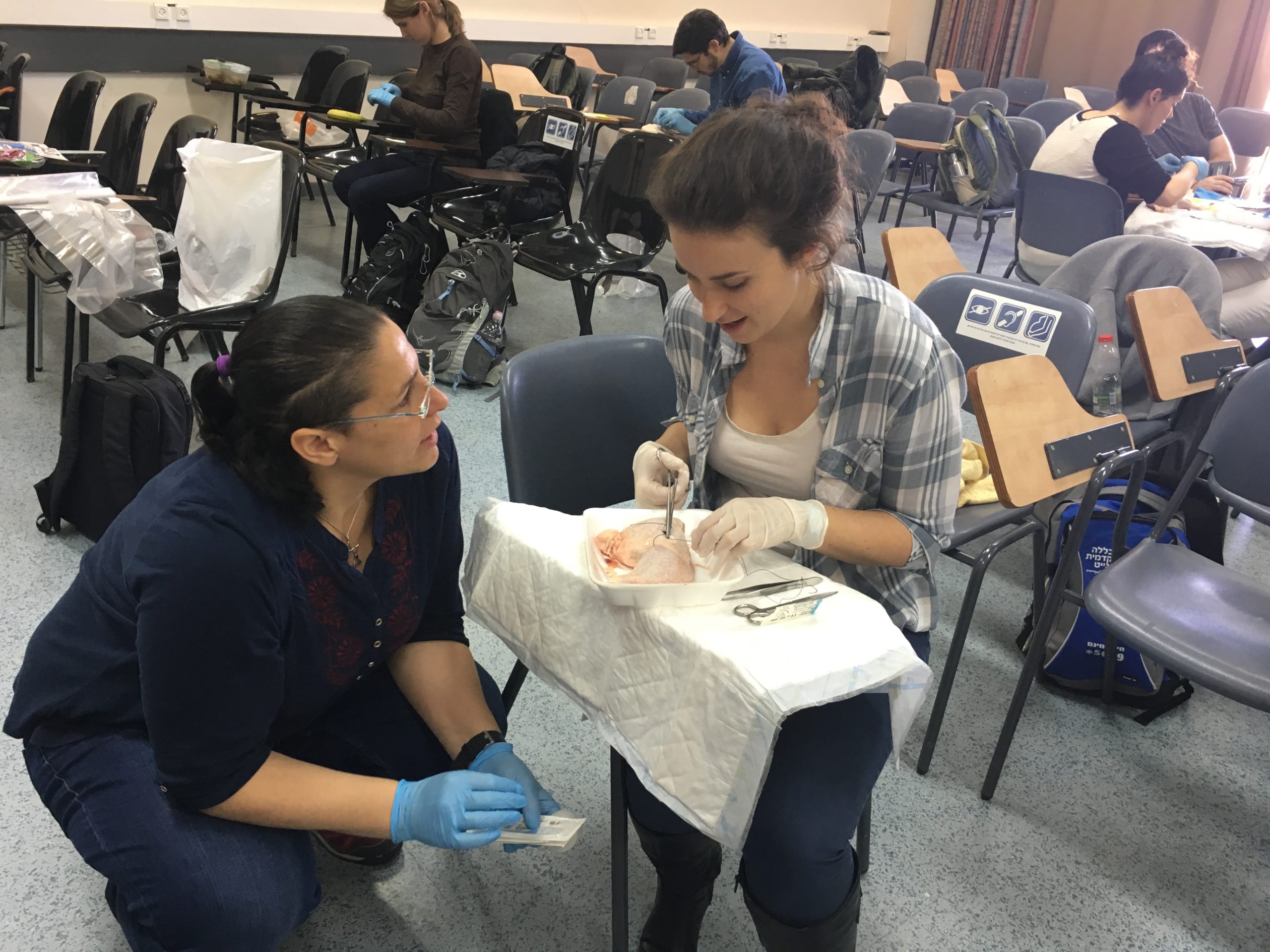 Female student practicing putting sutures in chicken legs